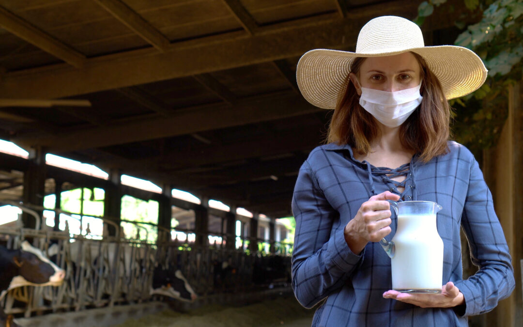 dairy farmer wearing mask holds milk jug